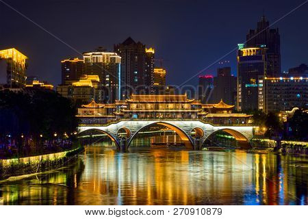 Famous landmark of Chengdu - Anshun bridge over Jin River illuminated at night with modern skyscrapers in background, Chengdu, Sichuan , China