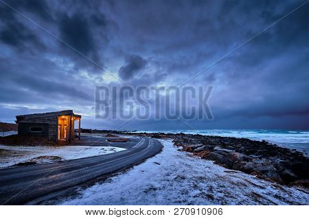 Shack on coast of Norwegian sea in fjord. Skagsanden beach, Flakstad, Lofoten islands, Norway in stormy evening