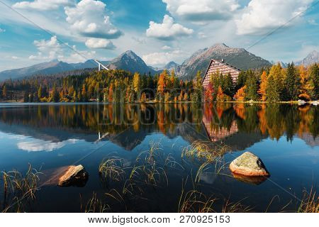 Picturesque autumn view of lake Strbske pleso in High Tatras National Park, Slovakia. Clear water with reflections of orange larch and high mountains on background. Landscape photography