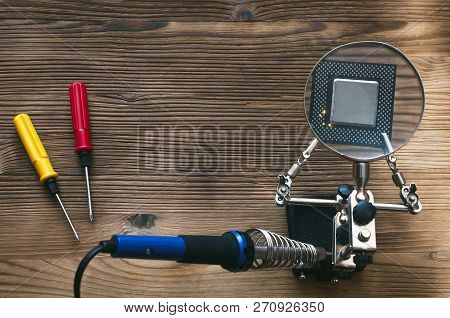 Retro Computer Cpu Chip Through Magnifying Glass Mounted On The Soldering Stand And Soldering Iron O