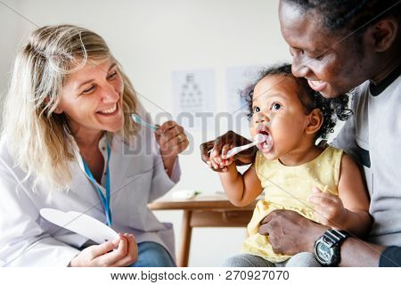 Dentist teaching a little girl how to brush her teeth