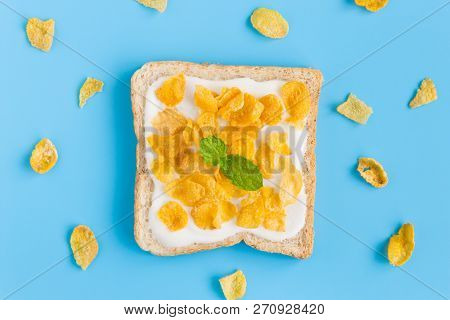 Cornflakes On Yogurt With Bread With Peppermint And Cornflakes On Blue Pastel Background Flatlay. Ce