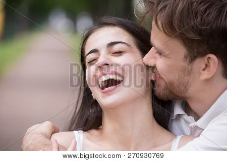 Loving Man Tickling And Embracing Laughing Woman Outdoors