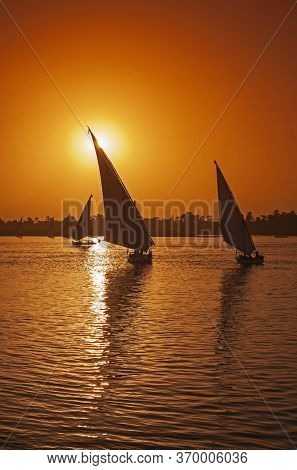 Traditional Egyptian Felluca River Boats Sailing On The Nile River Bank With Sunset And Reflection I