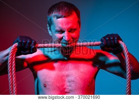 Studio Image Of A Man In Gloves Bites A Rope