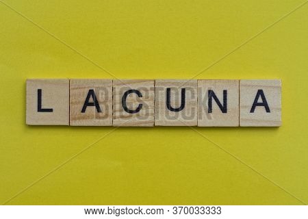 The Gray Word Lacuna Of Gray Small Wooden Letters Lie On A Yellow Table