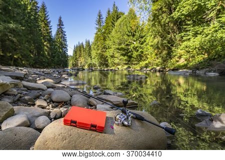 Fishing Tackle Set On Stone At Wild Mountain River. Spinning Rod With Reel, Box, Lures, Lure Box, Sp