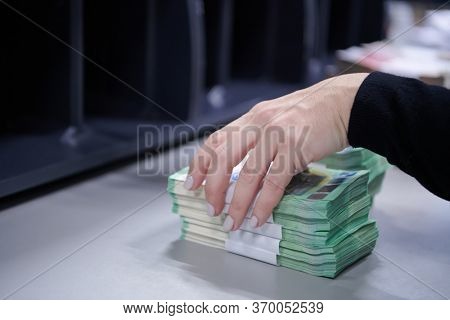 Bank employees using money counting machine while sorting and counting paper banknotes inside bank vault. Large amounts of money in the bank