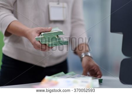 Bank employees using money counting machine while sorting and counting paper banknotes inside bank vault. Large amounts of money in the bank