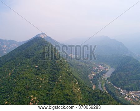 Aerial View Of Green Mountain Peak With Small Village And Blue Sky. Landscape Of Mountain In Natural