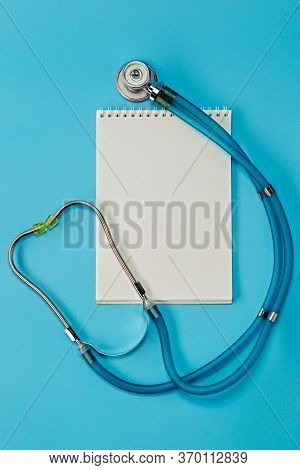 A Stethoscope And Notepad On Blue Doctor Table Or Nurse Desk. Health Checkup. Medical Healthcare And
