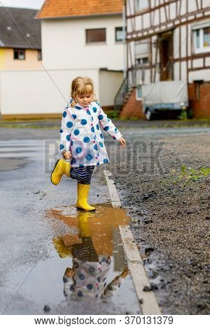 Little Toddler Girl Wearing Yellow Rain Boots, Running And Walking During Sleet On Rainy Cloudy Day.