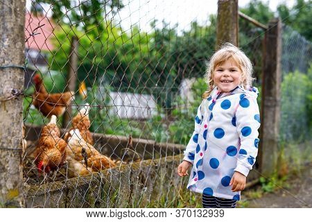 Outdoor Portrait Of Happy Smiling Little Toddler Girl Wearing Rain Jacket On Rainy Cloudy Day Feedin