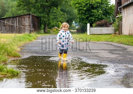 Little Toddler Girl Wearing Yellow Rain Boots, Running And Walking During Sleet On Rainy Cloudy Day.