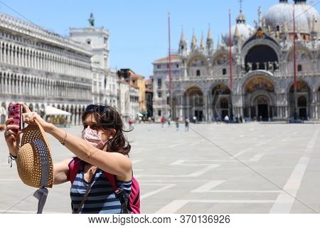 Pretty Woman With Mask Makes A Selfie With The Smart Phone In The Deserted Piazza San Marco In Venic