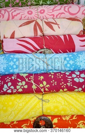 Rolled Up Colored Fabrics Tied With String. Shop With Brightly Colored Sarongs. Sarung Pantai Ready 