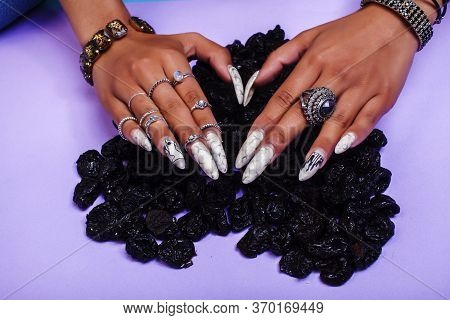 Woman Hands With Long Nails Manicure Holding Dry Fruits In Shape Of Heart On Purple Background