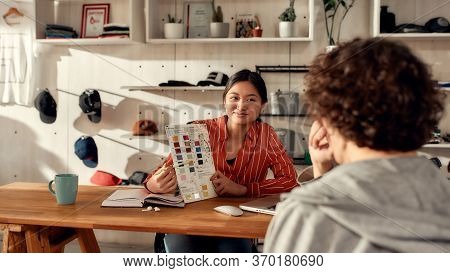 Portrait Of Young Worker Showing Color Samples Of Fabric To Male Customer In The Office. Woman Worki