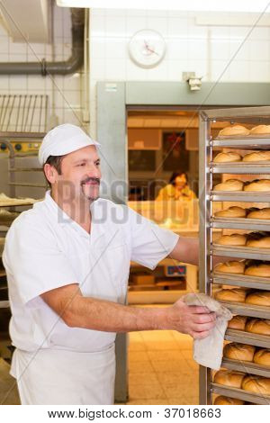 padeiro em pé na sua padaria na parte da manhã e assa pão ou pãezinhos