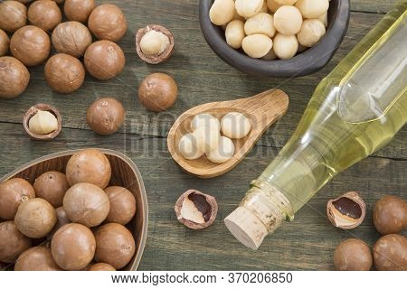 Nuts And Macadamia Oil On Wooden Background - Macadamia Integrifolia