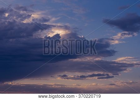 Dramatic rainy clouds on purple evening sky. Natural background with stormclouds and sunlights of se