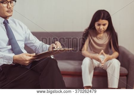 Professional Psychologist Talking With Asian Woman Patient And Writing Notes,therapist Conducting A 