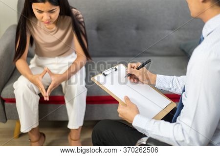 Professional Psychologist Man Talking With Asian Woman Patient And Writing Notes,therapist Conductin