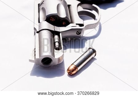 A Stainless Snub Nosed 357 Magnum Revolver With A Hollow Point Bullet Next To It On A White Backgrou