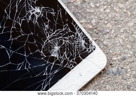 Smartphone With Broken Blue Display Screen Is Lying On The Asphalt. Closeup, Selective Focus