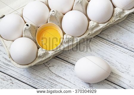 Close-up Of Fresh White Organic Chicken Eggs In The Paper Tray And Egg Yolk On Light Wooden Backgrou