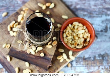 Selective Focus. A Glass Of Black Soda Drink And Peanuts. Salted Peanuts In A Glass With Coke. Ameri