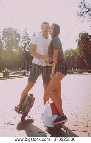 Young Couple Driving On Monowheel In The Park