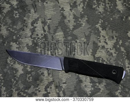 A Knife With A Black Handle Lies On The Camouflage Fabric
