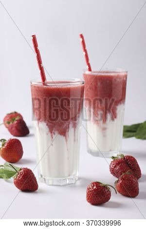 Two Servings Of Homemade Double Layer Smoothies With Fresh Strawberries, Mint And Yogurt In Glasses 