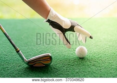 Female Hand Wearing White Professional Gloves With The Left Hand Putting Golfball And The Putter Gol