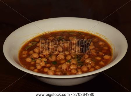Side Angle Shot Of Traditional Indian Chole Or Chola (chickpea Dish) Served Hot On A White Plate. It