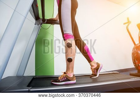Young Sports Woman With Electrostimulator On The Muscles Of The Legs.