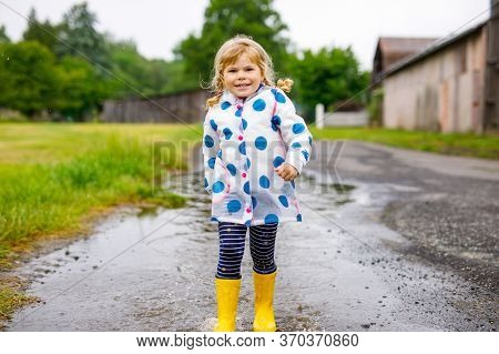 Little Toddler Girl Wearing Yellow Rain Boots, Running And Walking During Sleet On Rainy Cloudy Day.