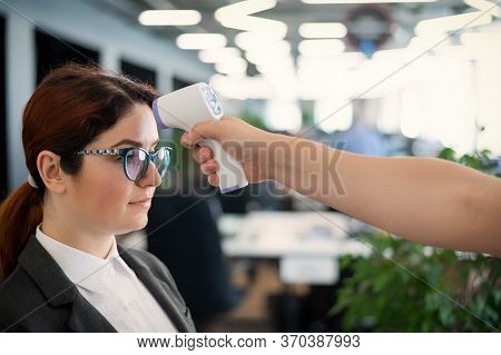 Temperature Measurement By Electronic Infrared Thermometer For Office Staff. Sick Woman In A Suit. C