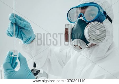 COVID-19. Doctor, microbiologist, scientist in a protective suit, makes a study of blood samples with coronavirus in the laboratory. 