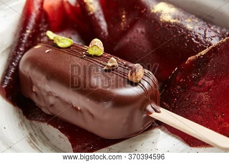 Chocolate mousse dessert close up. Luxury restaurant sweet course side view. Ice cream served with pastila in deep craft plate. Fancy confectionery dish with jellied fruit sweetmeat. Sweet food