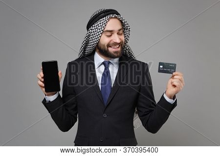 Smiling Arabian Muslim Businessman In Keffiyeh Kafiya Ring Igal Agal Suit Isolated On Gray Backgroun