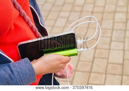 Girl Holds A Smartphone And An External Power Bank While Charging