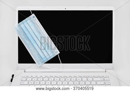 Concept Work From Home. Blue Protective Madical Face Mask Is On The Momitor Of Laptop. Quarantine Du