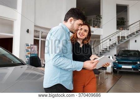 Couple Looking At Car Dealership Catalog. Young Couple