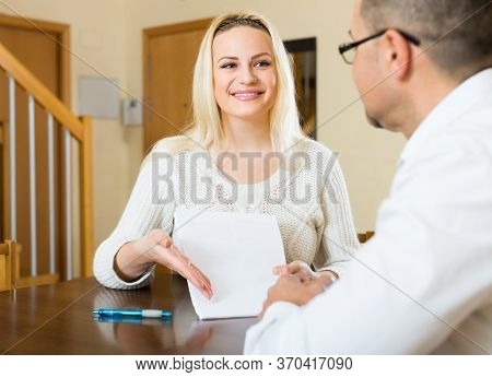 Attractive Blonde Woman Talking With Agent Or Employee With Documents At Home.