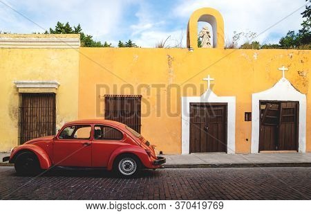 Merica, Yucatan, Mexico - 28 October 2018 - Red Oldtimer Volkswagen Beetle In The Colonial Historica