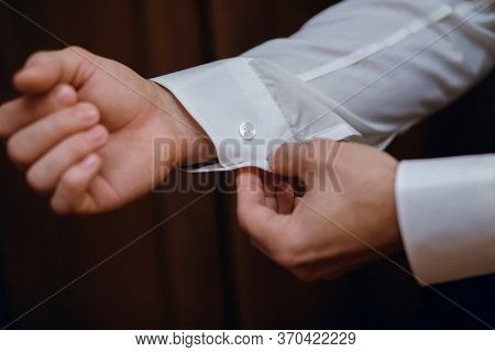 A Man Fastens The Sleeves Of His Shirt, Close-up, White Shirt, On A Brown Background, Stylish Male B