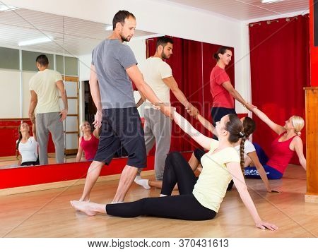 Cheerful Adults Learning How To Dance Tango In Dancing Hall. Men Picking Up Women From Floor