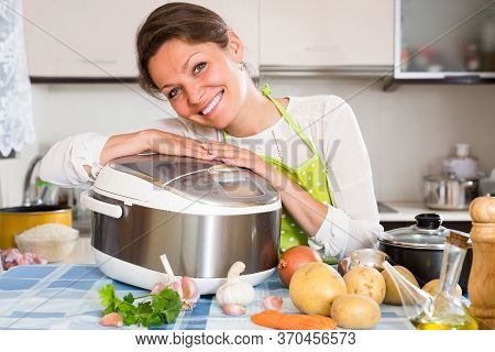 Happy Smiling Housewife Cooking With New Electric Multicooker At Home Kitchen.